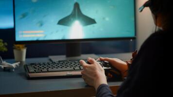 Closeup of competitive woman player holding joystick playing space shooter games at powerful computer late night. Professional gamer using wireless controller for online gaming championship photo