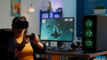 Videogame player with vr goggles raising hands after winning space shooter competition wearing headset dancing. Professional pro cyber woman playing online game with new graphics on powerful computer photo
