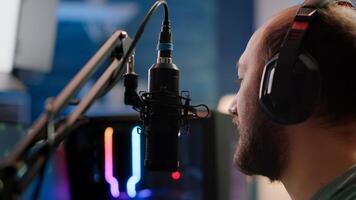 Portrait of cyber talking on stream chat with players using micorphone and powerful computer. Streamer man sitting on gaming chair playing space shooter game during online esports tournament. photo