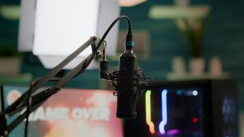 Streaming professsional microphone in empty gaming home studio with neon lights. Game is over on display of RGB professional powerful computer and stream chat is prepared for virtual tournament photo