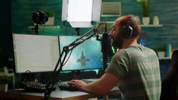 Pro cyber man streaming videogame, reading on stream chat and playing space shooter on RGB powerful computer. Streamer sitting on gaming chair playing game during online esports tournament. photo