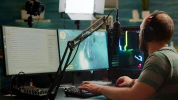 Over shoulder footage of professional streamer with headset playing digital space shooter games on RGB powerful computer using microphone and mouse. Videogamer man streaming online games photo