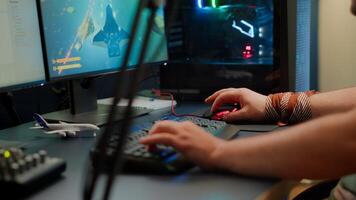 Close up of player hands using RGB keyboard in gaming home studio streaming space shooter game. Digital gamer using professional equipment for game competition late at night in living room photo