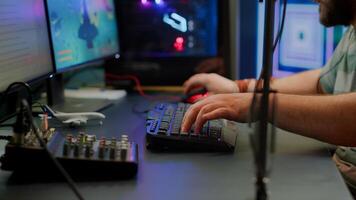 Close up of streamer typing at RGB keyboard playing space shooter videogame. Pro cyber man using mixer sound in gaming home studio for online esports competition on professional powerful computer photo
