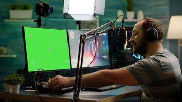 Professional cyber streamer playing online videogames on professional powerful computer with green screen mock up, chroma key display. Gamer playing space shooter game with isolated desktop streaming photo