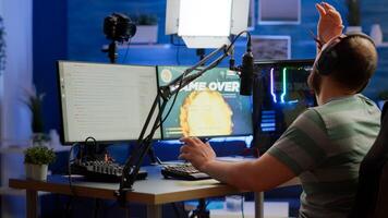 Videogame streamer losing online videogame competition wearing professional headset talking on stream chat. Sad gamer using powerful computer for gaming tournament late night playing space shooter game photo