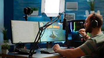 Streamer man talking with multiple players into headphones and winning games competition. Professional gamer streaming online videogames with new graphics on powerful computer from gaming room photo