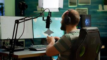 Man streamer playing space shooter games using professional RGB keyboard and wireless joystick. Pro gamer talking into microphone on streaming chat during online tournament photo