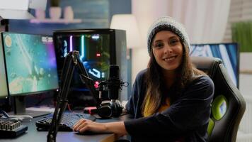 Portrait of woman streamer looking at camera after playing space shooter games using professional RGB keypad on powerful computer. Pro player streaming online videogames in gaming home studio photo