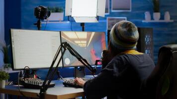 Streamer coming in gaming room playing videogames and talking with team mates on streaming open chat and microphone, checking sound mixer. Cyber performing on powerful computer professional equipment photo