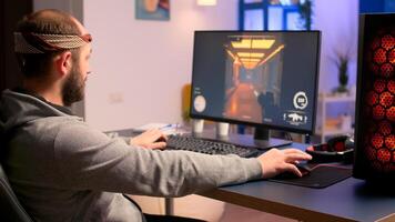 Caucasian man playing online games for virtual championship using professional RGB system desktop. Pro gamer siiting on gaming chair looking and smiling at camera late at nigh in home studio. photo