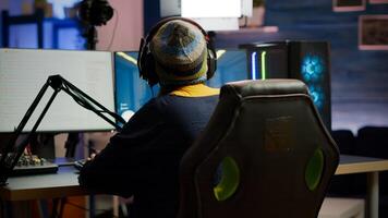 Back shot of pro gamer woman playing first person games using RGB keyboard in home studio. Gamer streaming gameplay using professional gaming powerful computer during online competition photo