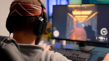 Pro gamer playing on powerful computer first person shooter game during live championship, wearing headphones. Competitive player streaming game tournament using professional equipment photo