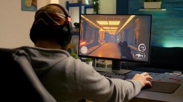 Back of pro gamer playing first person shooter game on professional computer for cyber esport competition. Pro player talking with multiple players using headset during online tournament photo