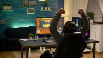 Videogamer player raising hands after winning first person shooter competition wearing hradphones. Professional pro gamer playing online games with new graphics on powerful computer photo