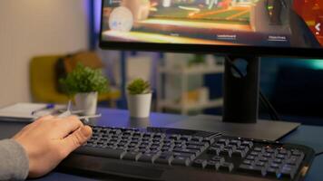 Close-up of player using RGB keyboard during online space shooter tournament. Pro gamer playing digital games on powerful computer late at night in gaming home studio photo