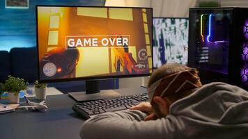 Digital gamer keeping his head on the office after losing first person shooter competition. Professional pro gamer playing online games with new graphics on powerful computer from gaming room photo
