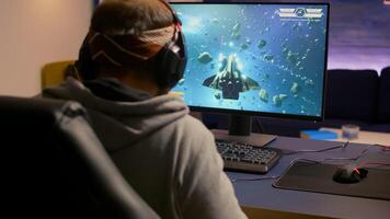 Pro gamer winning space shooter game use wireless joystick. Competitive player using modern technology for online championship sitting on gaming chair late at night in living room photo