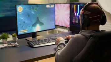 Back shot of pro gamer playing online space game on powerful computer using wireless controller. Competitive player man using professional RGB equipment during game tournament photo