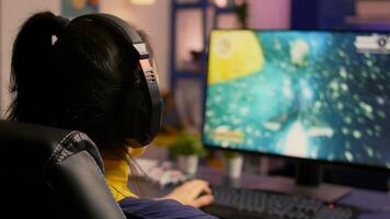 Close-up of gamer sitting on gaming chair and playing space shooter online game for virtual tournament. Player man with headphones streaming games in a room with neon light and modern equipment photo
