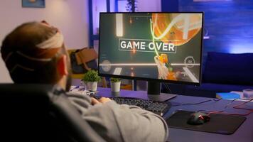 Game over for upset gamer playing on powerful computer first person shooter game during online tournament. Defeated man with headphones streaming online cyber performing late at night in gaming room photo