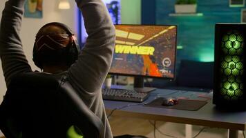 Videogamer playing graphics cyber space sitting on gaming chair using technology network wireless. Man streaming games online for fun using RGB equipment for online championship photo