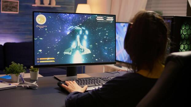 Player sitting on gaming chair and start playing space shooter game wearing professional headset. Modern studio equipped with RGB system desktop, keyboard, mouse, using technology network wireless photo