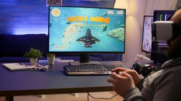 Pro gamer winning space shooter games using virtual reality headphones and controller. Competitive player man using professional equipment with new graphics on powerful computer from gaming room photo