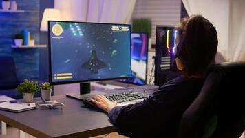 Pro gamer talking into microphone with other gamers during digital championship. Player wearing headphones and playing online games with new graphics on powerful computer from gaming room photo