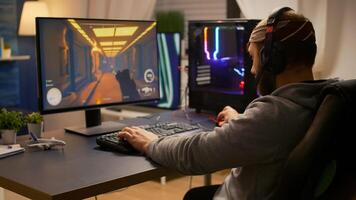 Videogamer winning first person shooter tournament using RGB keyboard and professional headphones. Pro player man talking with other players online for game competition on powerful computer photo