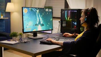 Gamer playing online space shooter games using powerful computer and RGB keyboard. Player wearing headphones and talking into microphone with other players for winning online tournament photo