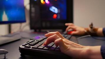 Close-up of gamer using RGB keyboard and mouse for online competition. Professional gamer playing space shooter games in gamming room with neon light photo