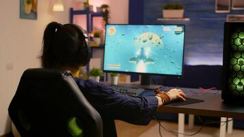 Winner gamer sitting on gaming chair at desk and playing space shooter games with RGB keyboard and mouse. Player streaming online games for esport tournament in room with neon lights photo