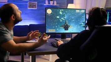 Couple of gamers making winner gesture while playing space shooter virtual championship. Defeated player with headphones streaming online cyber performing during online gaming competition. photo