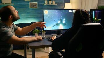 Couple of gamers losing space shooter tournament while playing in room with RGB. Defeated player with headphones streaming online cyber performing during online gaming competition. photo