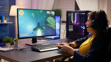 Pro player talking into microphone with other players for space shooter tournament. Gamer using wireless joystick for online championship on powerful computer late at night in gaming room photo