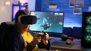 Winner gamer wearing virtual reality goggles, playing space shooter games in room with RGB. Pro game r using professional joystick during digital championship at gaming home studio photo