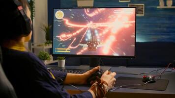Over shoulder of focused cyber player wearing headset during online championship. Game over for pro gamer using controller for space shooter gaming competition late at night in living room photo
