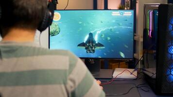 Over shoulder footage of professional streamer playing digital space shooter games on computer using headphones, microphone and mouse. Videogamer man streaming online games in room with RGB photo