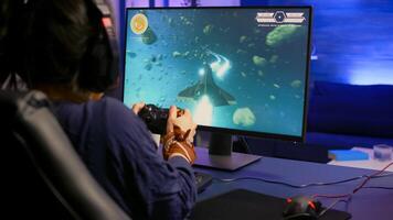 Back view of pro gamer winning space shooter game using headphones. Player using joystick for online championship sitting on gaming chair playing on professional powerful computer photo