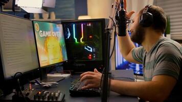 Game over for streamer playing space shooter games using professional RGB keyboard and mouse. Pro gamer talking into microphone on streaming chat during online tournament photo