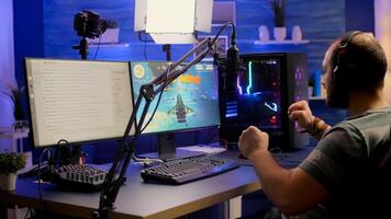 Streamer man winning space shooter online competition using professional microphone, keypad, mouse in gaming home studio. Player playing online games with streaming chat open during tournament photo