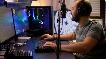 Pro gamer move the buttons on professional mixer late at night in streaming home studio. Streamer playing space shooter games tournament using RGB keyboard in room with neon lights. photo