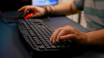 Close-up of streamer man playing space shooter game using RGB keyboard during esport tournament. Player performing online competition late at night in streaming home studio photo