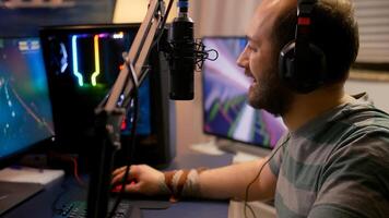 Pro gamer puts professional headphone and start playing space shooter game new graphics on powerful computer. Player using two monitors during online tournament at streaming hone studio photo