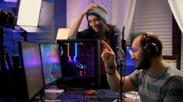 Side view of pro streamer couple performing online games using powerful computer with multiple monitors. Player playing space shooter games during e-sport online tournament in streaming studio photo