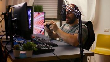 Side view of pro streamer man with headphones playing online games with streaming chat open. Cyber performing on powerful computer in gaming room home using professional console photo