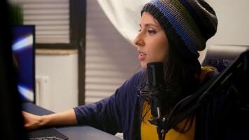Close-up of pro streamer woman talking into microphone during virual games competition. Gamer streaming playing online games using RGB keyboard mouse late at night in home studio photo