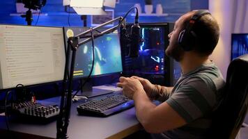 Back shot of pro streamer playing graphics cyber space shooter games using wireless joystick. Gamer performing on powerful pc talking with players on chat open during professional competition photo