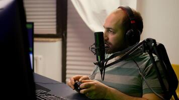 Close-up of pro streamer talking into professional microphone during virtual competition. Player streaming online games using wireless controller late at night in gaming home studio photo